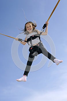 Young girl playing on bungee trampoline photo