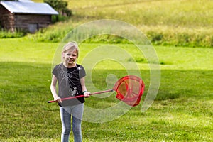 Young girl playing with a butterfly net on the meadow