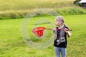 Young girl playing with a butterfly net on the meadow