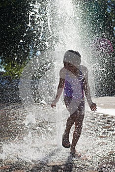 Young girl playing in a fountain .