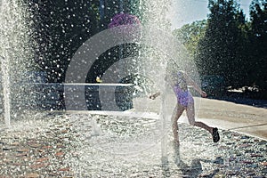 Young girl playing in a fountain .