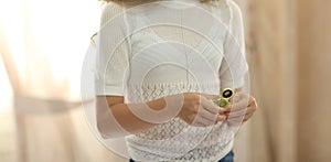 Young girl playing with green fidget spinner in bright room