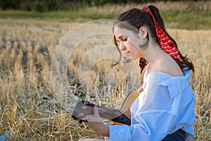 Young girl playing the guitar on straw field