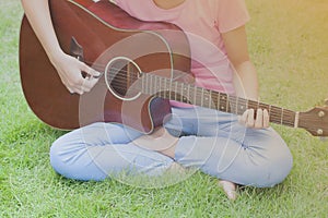 Young girl playing guitar, sunset vintage tone.