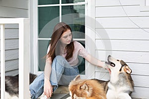 Young girl playing with her dog. Girl sitting on floor next to dogs lying at home