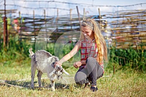 Young girl playing with a little goat in the village