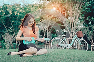 Young girl playing music ukulele outdoor