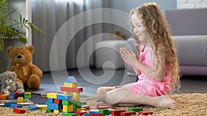Young girl playing organic wooden blocks, kids leisure at home, education