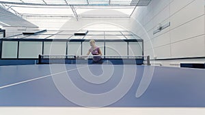 Young girl playing the ping-pong at the court