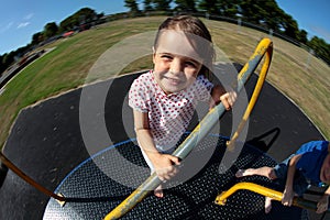 Young girl playing on roundabout in sunny park