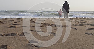 Young girl playing by the sea with her grandfather