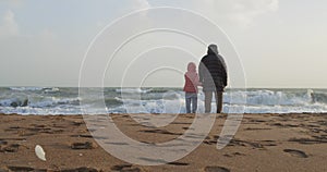 Young girl playing by the sea with her grandfather