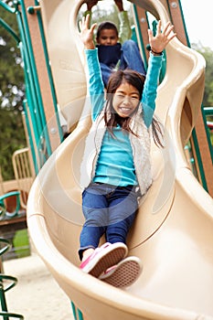 Young Girl Playing On Slide In Playground