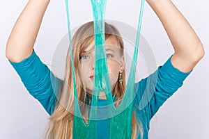 Young girl playing with slime holding it in front of her face