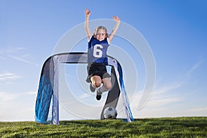 Young Girl playing soccer and scoring goal photo