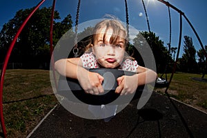 Young girl playing on swing in sunny park