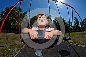 Young girl playing on swing in sunny park