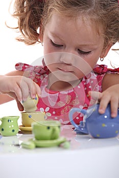 Young girl playing with a tea set