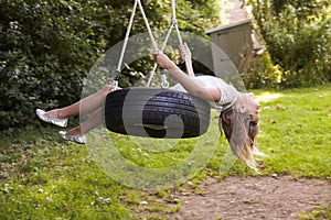 Young Girl Playing On Tire Swing In Garden