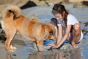 Young girl plays with her dog at the beach