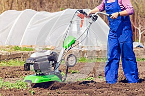 Young girl plows the land with a cultivator in spring garden