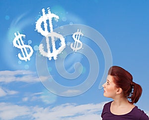 Young girl pointing at dollar sign clouds on blue sky