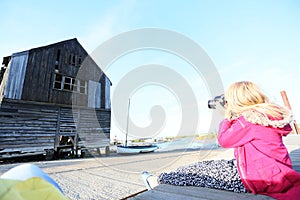 Young girl pointing her camera at an old barn