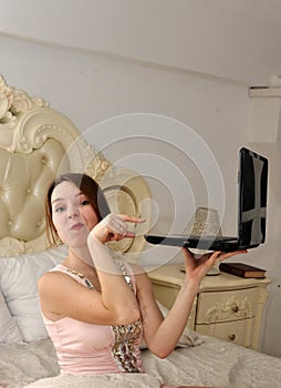A young girl pointing at laptop and ironic wrinkling his nose