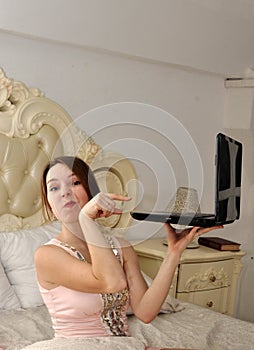 A young girl pointing at laptop and ironic wrinkling his nose photo