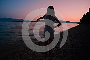 Young girl pointing to the horizon after sunset