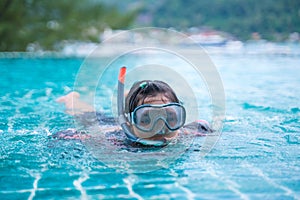 Young girl in pool with swimming mask and snorkel