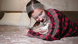 Young girl portrait close-up lying on the bed stroking a cat, Pets. authentic video, friendship, love, the comfort of