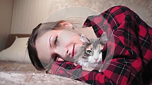 Young girl portrait with a pet, a cat lying on the sofa, stroking the cat.