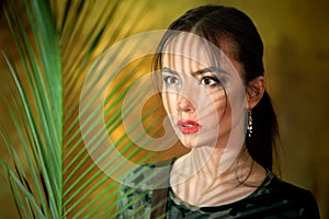 A young girl portrait with shadows from with palm leaves dressed up as a cosplay woman in jungle