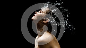 Young girl portrait and splash water in her face. beautiful female model on black background.