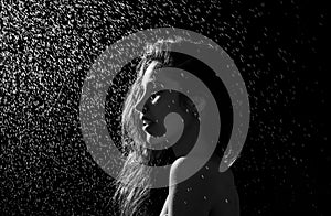 Young girl portrait and splashing water in her face. beautiful female model on black background.