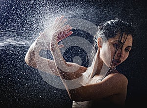 Young girl portrait and splashing water in her face. beautiful female model on black background.