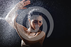 Young girl portrait and splashing water in her face. beautiful female model on black background.