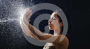 Young girl portrait and splashing water in her face. beautiful female model on black background.