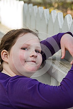 Young girl posing leaning on picket fence