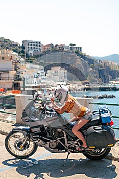 Young girl posing. Motorcycle for tourism and travel. Wearing a helmet. In the background are views of the sea and hotels. Coast