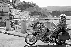 Young girl posing. Motorcycle for tourism and travel. Wearing a helmet. In the background are views of the sea and hotels. Coast