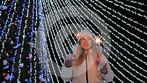 Young girl posing with sparklers against the background of New Year& x27;s daisies.