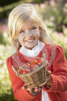 Young girl posing with tomatoes in garden