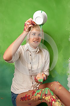 Young girl pouring a green paint on herself from a cup