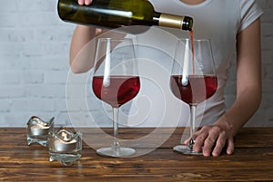 Young girl pouring red wine into glass on romantic party
