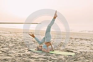 A young girl practices yoga on the beach. Sports, fitness, yoga. The concept of care and healthy lifestyle