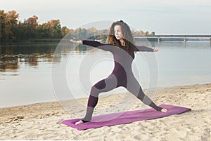 A young girl practices yoga by the river.