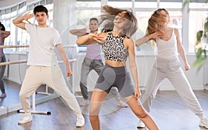 Young girl practicing hip-hop dance in training hall in group