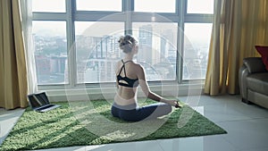 Young girl practicing yoga at home with cityscape background